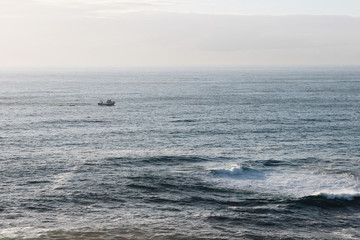 Fishing boat leaving land at sunset in the coast of Galicia, Spain
