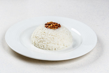 White rice circle shape in a ceramic dish served with fried pine nuts