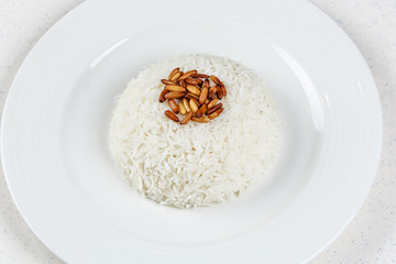 White rice circle shape in a ceramic dish served with fried pine nuts