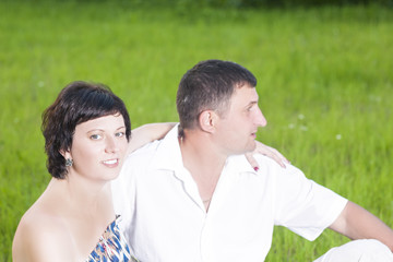 Family Relationships Concepts. Portrait of Caucasian Couple Relaxing Together Outdoors on Grass in Park. Sitting Embraced