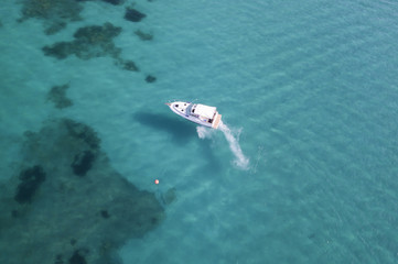 Aerial view of a little yacht on amazing beach with a turquoise and transparent sea. Emerald Coast, Sardinia, Italy.