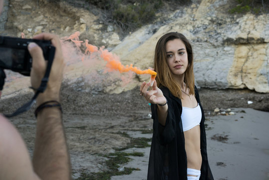 Man taking a photo girl with colored smoke on beach
