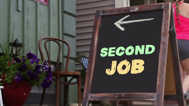 Woman walks past a sign that reads Second Job and points to small business