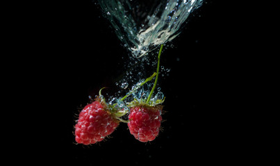 Fototapeta na wymiar Raspberrie falling underwater with bubbles on black background