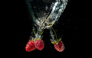 Raspberrie falling underwater with bubbles on black background