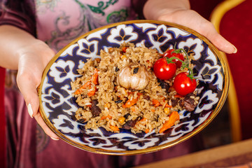 hand holding national dish of uzbek pilaf with vegetables