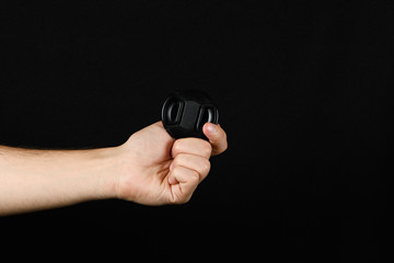 In the male hand a lens cap isolated on black background