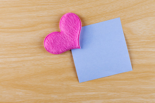 blank sticky note paper with pink heart shape on the wooden background
