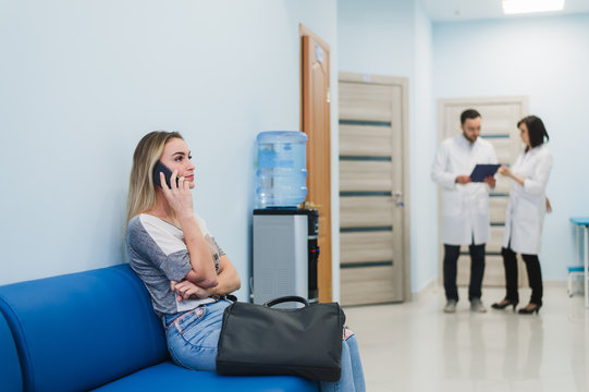 Woman Patient In Speaking At The Mobile Phone In Hospital Waiting Room.