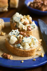 Brotscheiben mit Blauschimmelkäse und Walnuss, fotografiert mit natürlichem Licht (Selektiver Fokus, Fokus auf die Vorderseite des ersten Brotes)