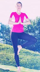 Portrait of sportswoman is staying and practising meditation in pink T-shirt
