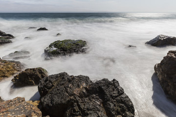 Malibu coast rocks with motion blur water at Point Dume near Los Angeles California.