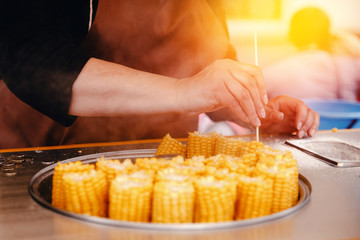 seller sells boiled yellow corn and salt outside the premises. Concept of street trading.