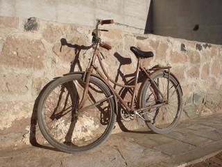 bicicleta marrom sombra no muro de pedra
