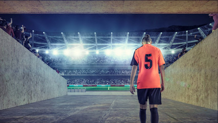 Naklejka na ściany i meble female soccer player entering the field on crowded stadium