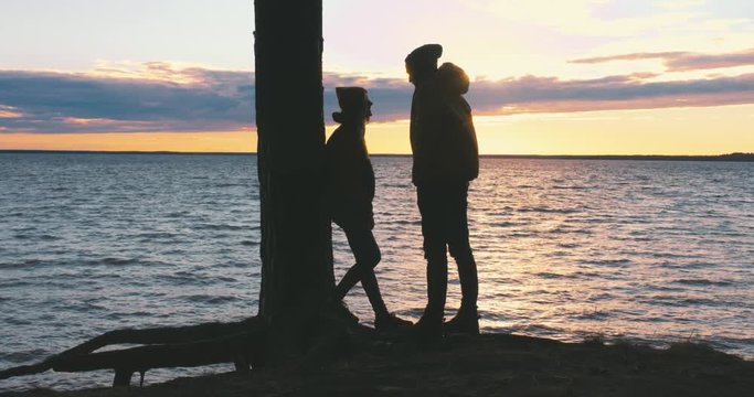 Outdoor portrait of young Caucasian hiker couple enjoying the view of a sunset over the large lake. 4K UHD 60 FPS slow motion
