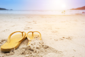 Fototapeta na wymiar Summer holiday on the beach yellow sandals on the beach have sunset