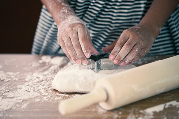Little child girl hands prepares a dough for baking cookies in the kitchen in vintage color tone