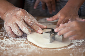 Mother and daughter hands prepare a dough for baking cookies together in the kitchen in vintage color tone