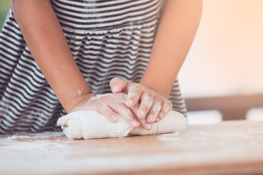 Little child girl hands kneading dough prepare for baking cookies in vintage color tone