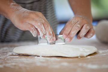 Little child girl hands prepares a dough for baking cookies in the kitchen
