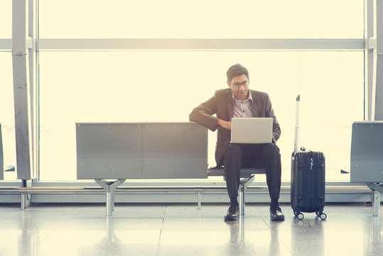 Asian Indian Business Man Sitting On Chair And Using Laptop While Waiting His Flight At Airport.