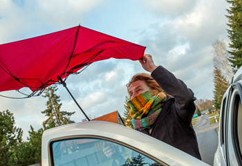 eine Frau hält bei Sturm ihren Regenschirm fest
