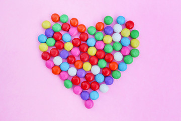 Colorful candies heart shape on pink
