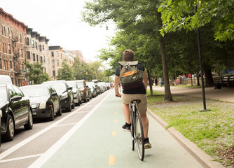 Back view of young hipster caucasian man riding bike on bike lane