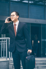 young businessman walking outside office,talking on the celephone.