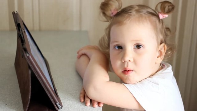 A cute little baby girl watching a movie on an tablet