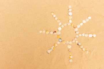 abstract sun image made of seashells on a sand