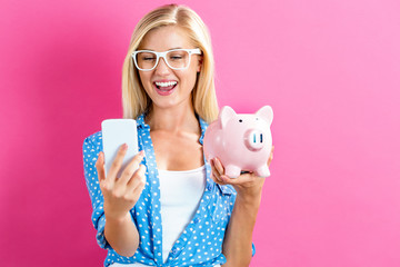 Young woman with a piggy bank on a pink background