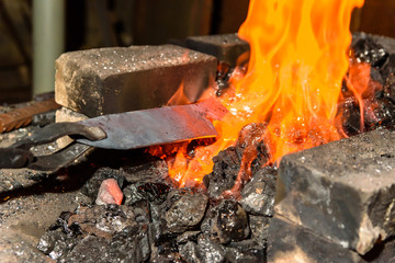 Warming up the metal in heat. The forge.