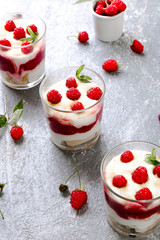 Tiramisu with raspberry in glasses on grey background. Three portion. Italian dessert