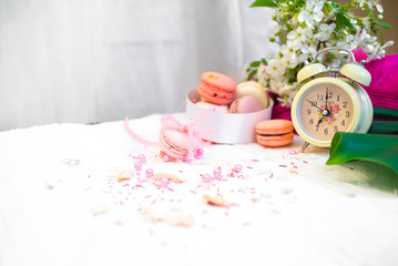 Tender pastel pink and orange macaroons on a white blanket and background