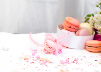 Tender pastel pink and orange macaroons on a white blanket and background