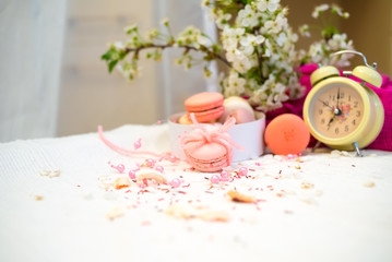 Tender pastel pink and orange macaroons on a white blanket and background