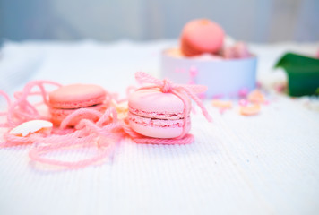 Tender pastel pink and orange macaroons on a white blanket and background