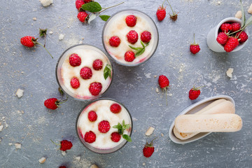 Tiramisu with raspberry in glasses on grey background. Three portion. Italian dessert. Top view.