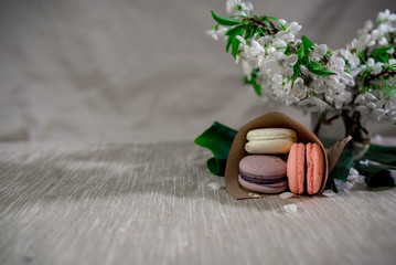 Multicolored macarons in metal silver vase on a pastel background with hot cocoa drink