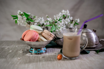 Multicolored macarons in metal silver vase on a pastel background with hot cocoa drink