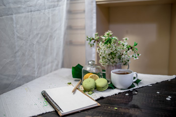 Morning tea or coffee with orange and kiwies slices and green macaroons on a white blanket with cherry blossom