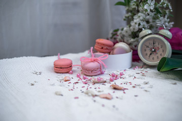 Tender pastel pink and orange macaroons on a white blanket and background