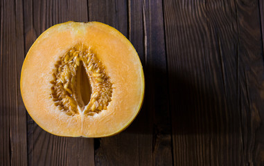 Melon cut in half on a wooden background (Top view)