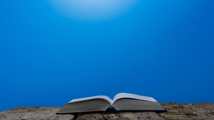 Bible and a crucifix on a old table. Beautiful blue background.Religion concept.