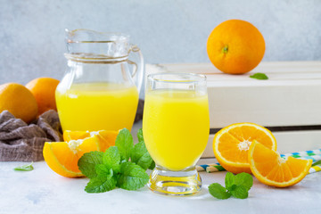 Naklejka na ściany i meble A refreshing summer drink with orange juice, fresh oranges and mint on a gray stone or slate background.