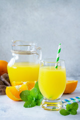 Naklejka na ściany i meble A refreshing summer drink with orange juice, fresh oranges and mint on a gray stone or slate background.