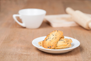 Home made a small sweet cookie with black sesame, typically round, flat, and crisp.Cookie in dish on wood.
