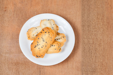 Home made a small sweet cookie with black sesame, typically round, flat, and crisp.Cookie in dish on wood.